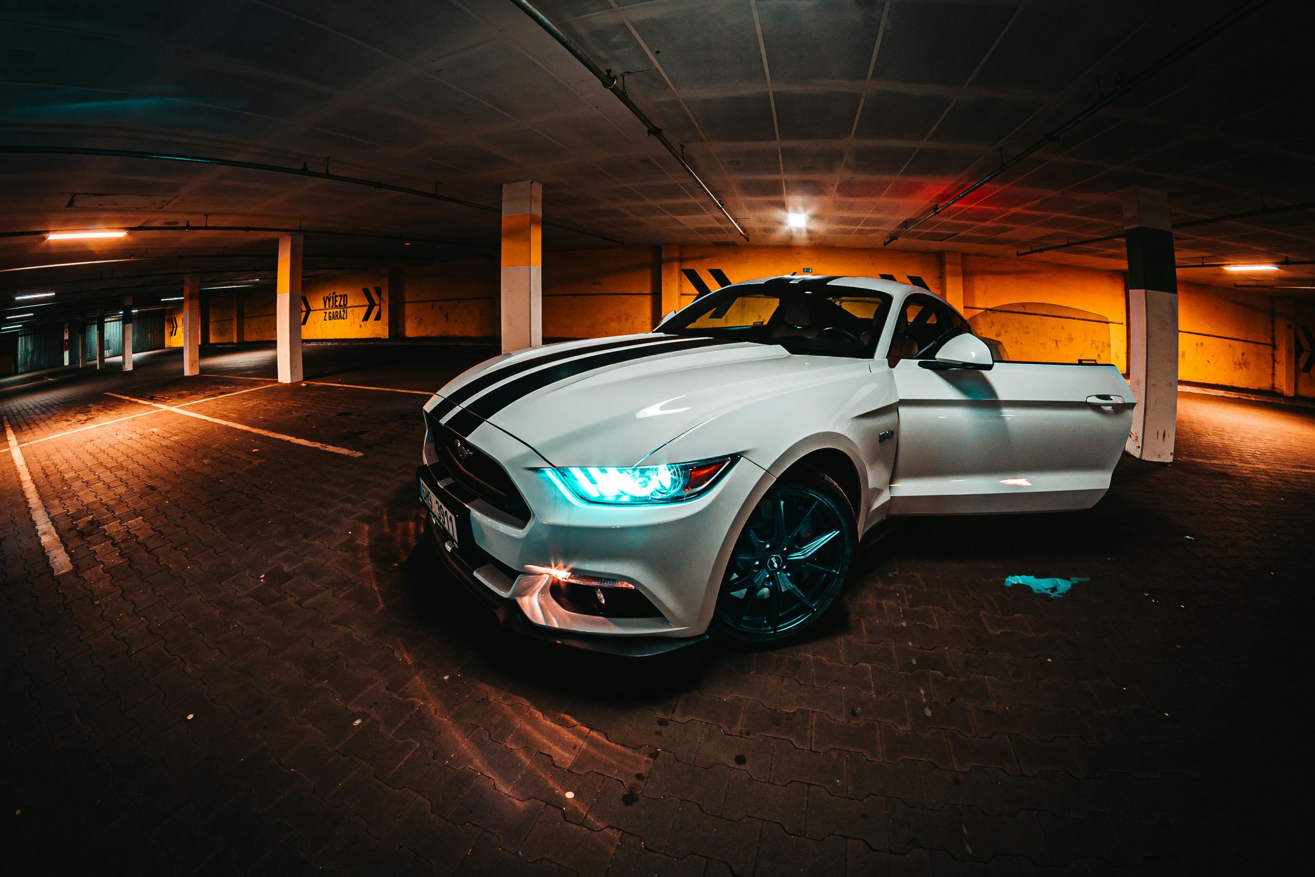 modern white muscle car with black vertical stripes on the hood