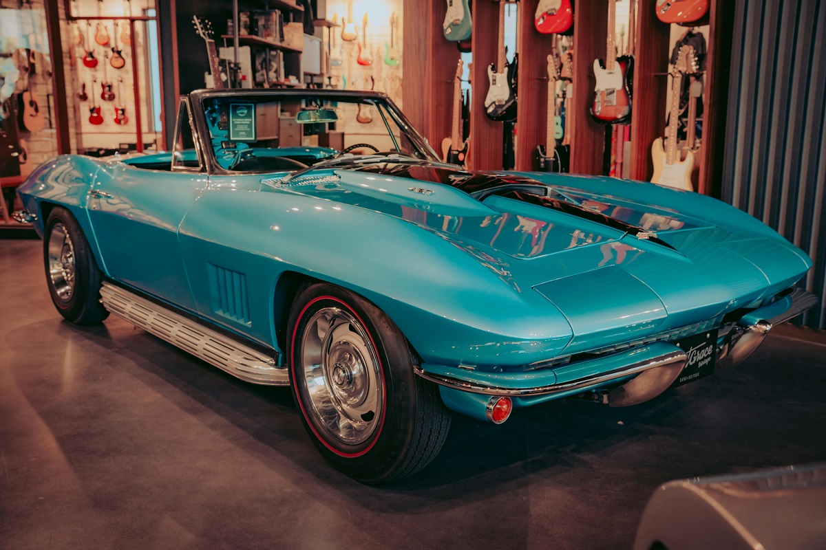 blue corvette convertible displayed in a room with electric guitars