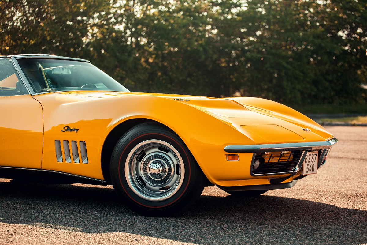 yellow corvette with trees in the background on a sunny day