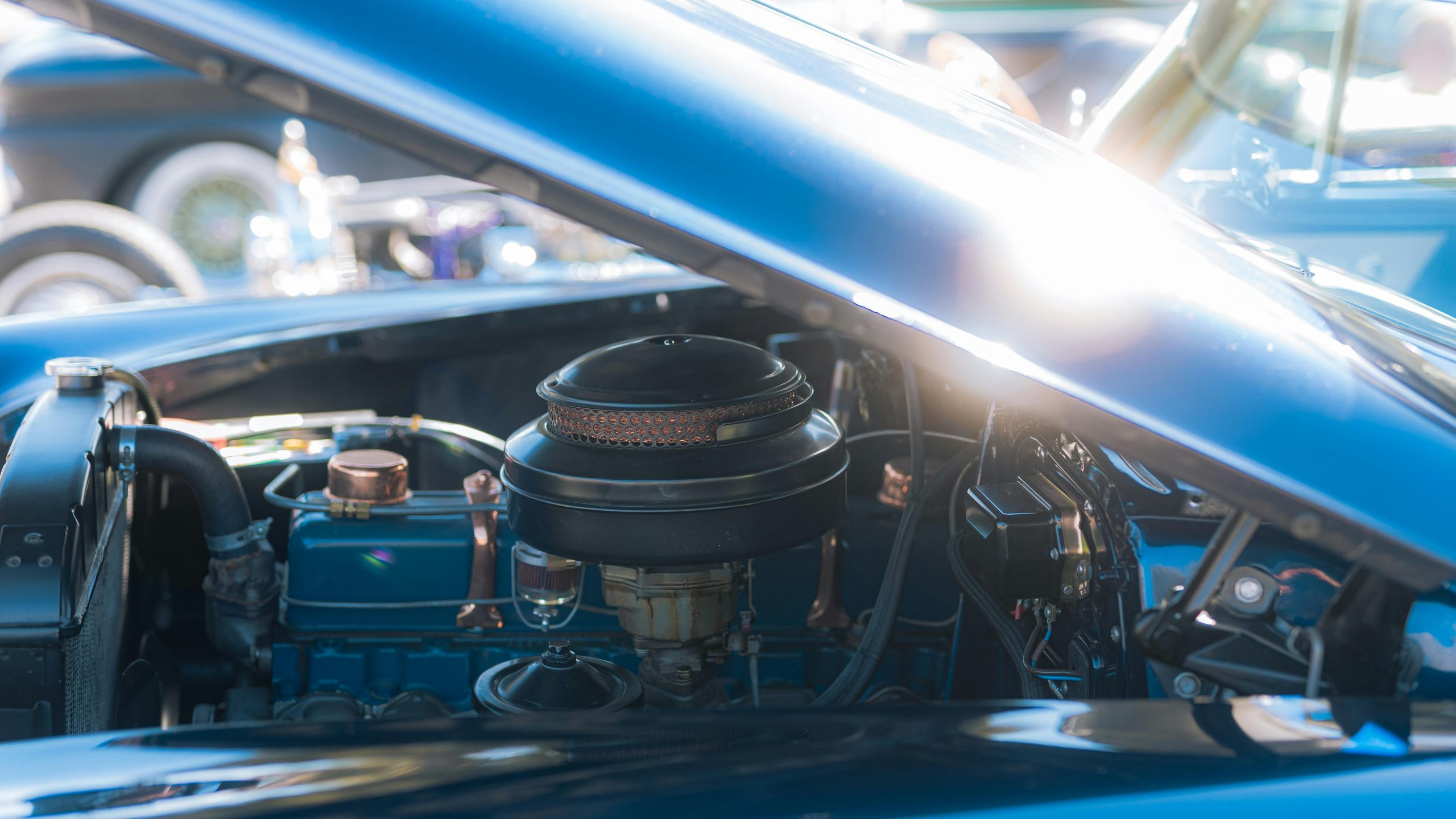 blue classic car with its hood open, revealing the engine